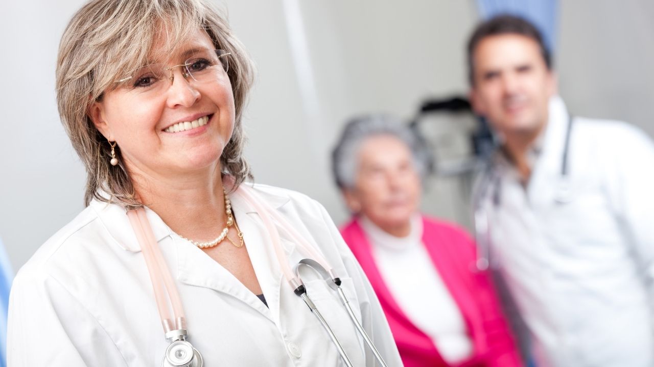 one female doctor in the forefront, and an elderly lady and male doctor in the background